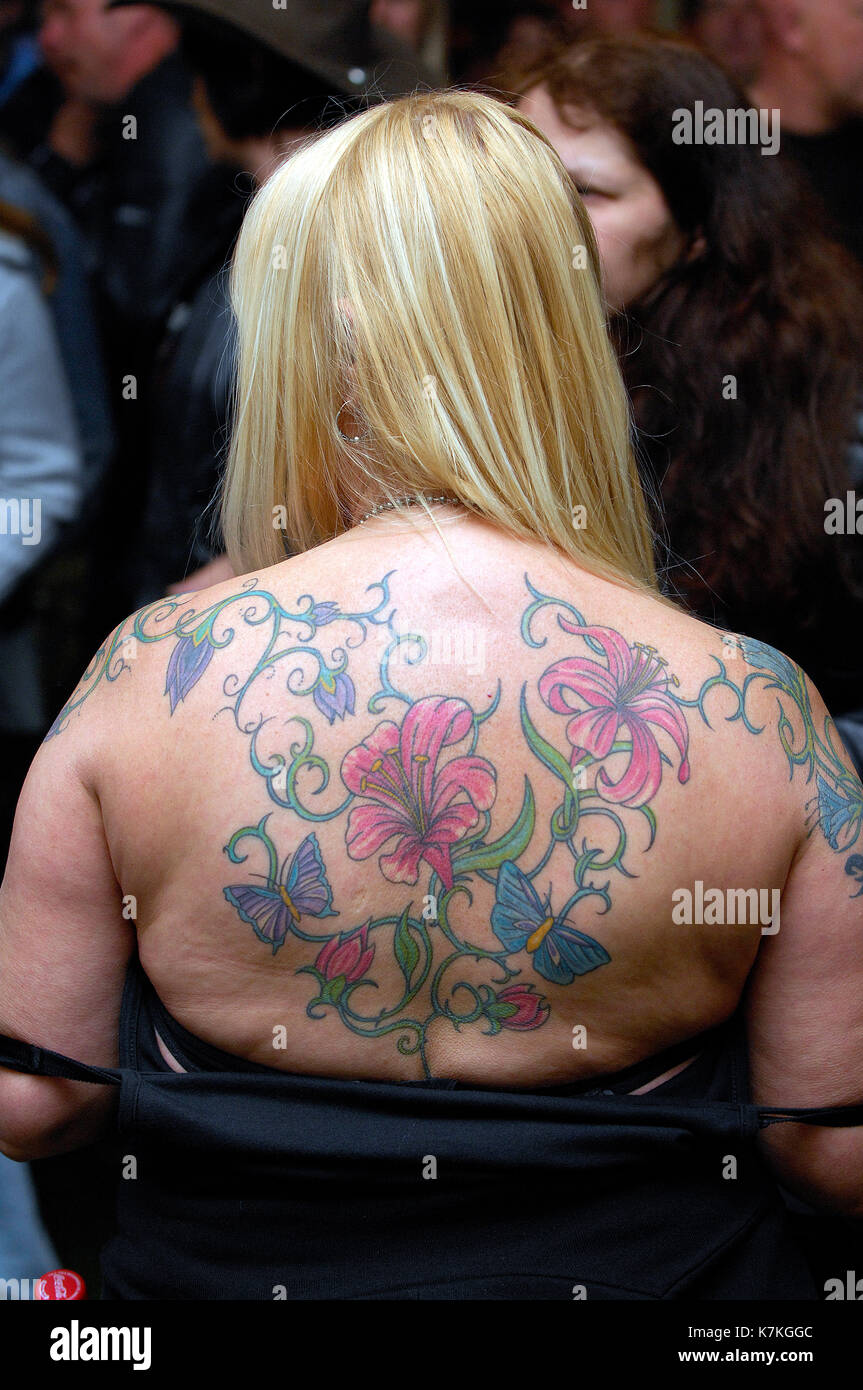 A woman with her back heavily tattooed having undergone extensive body art with long blond hair. Stock Photo