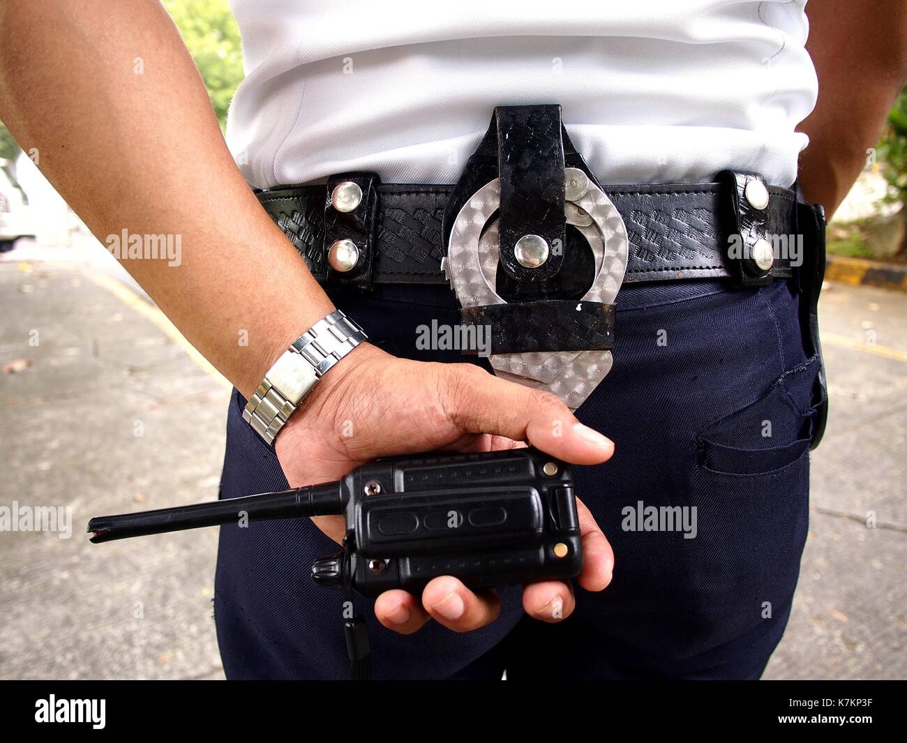 Photo of a security guard holding a two way radio with handcuffs on his belt Stock Photo