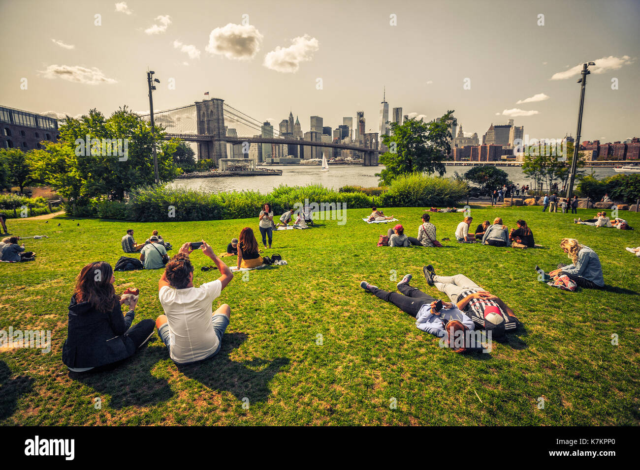 People enjoying free time on view to Brooklyn Bridge and Manhattan from Brooklyn side Stock Photo