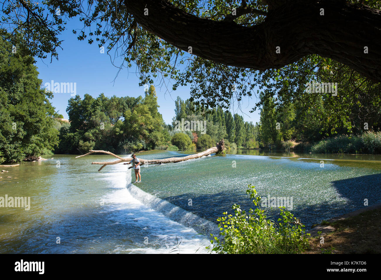 Fisherman fishing on weir on gently flowing River Duero in Castile and