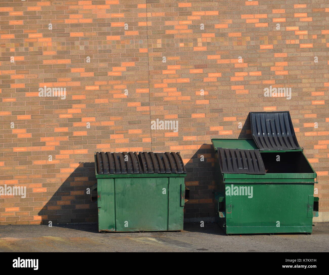 Green recycling dumpsters against a brick wall Stock Photo Alamy