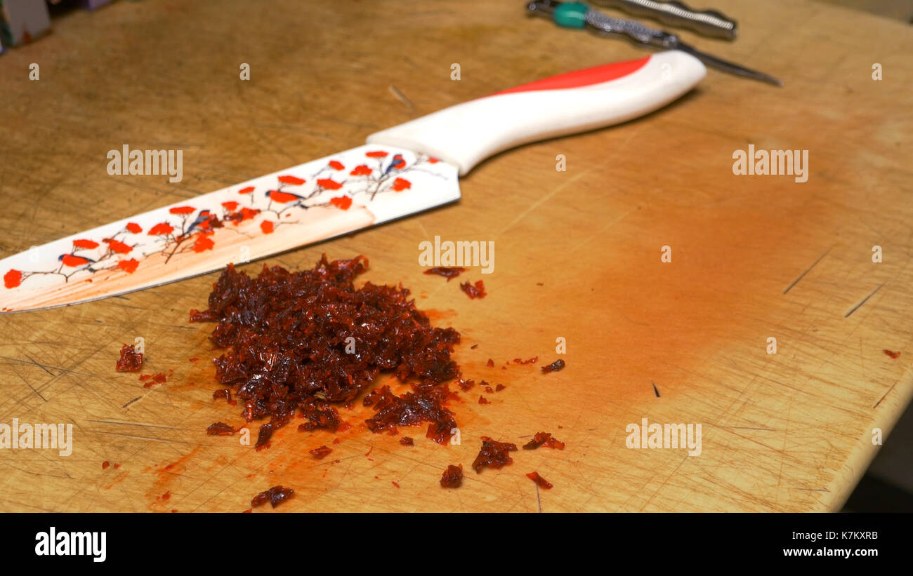 Man's hand with knife cutting pipe tobacco for Hookah. Tobacco preparation. Dry fruits for