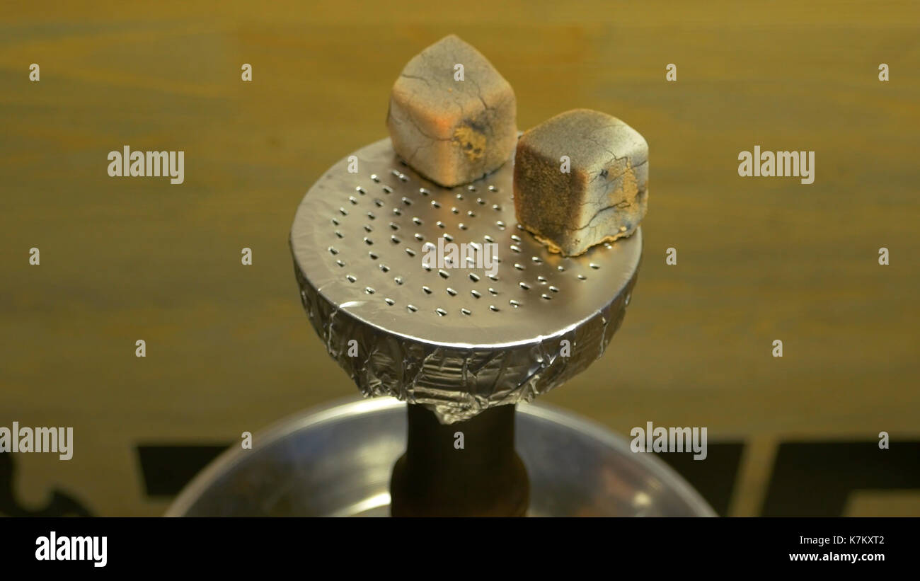 Man's hand puts burning coals on clay bowl with tobacco for hookah