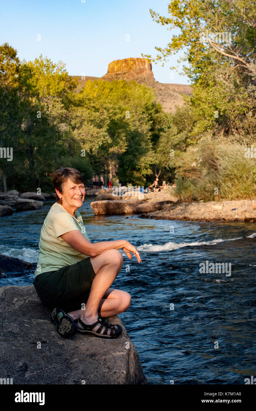 Woman sitting by Clear Creek - Golden, Colorado, USA Stock Photo