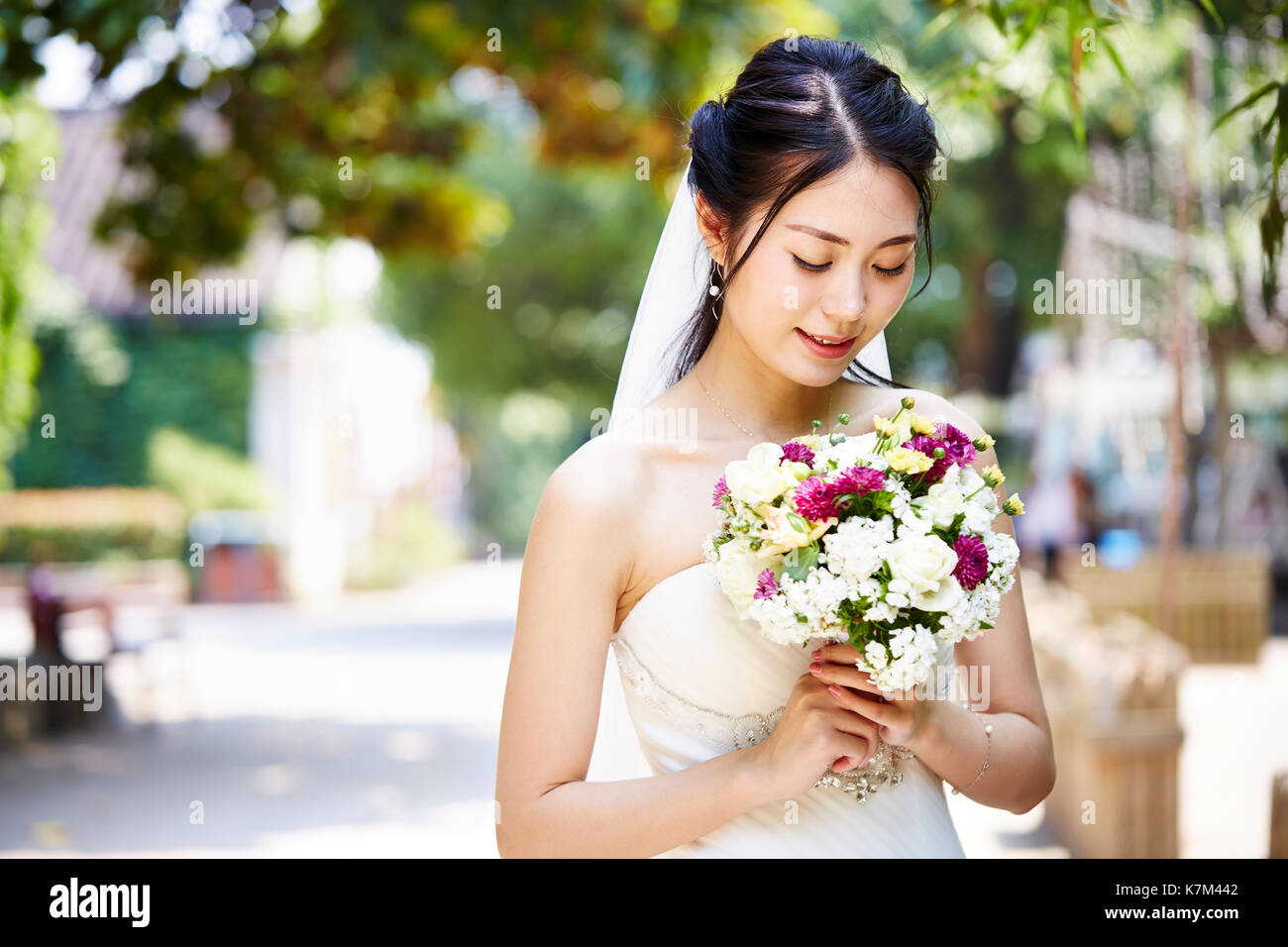 beautiful and happy young asian bride wearing bridal veil holding a bunch of flower. Stock Photo