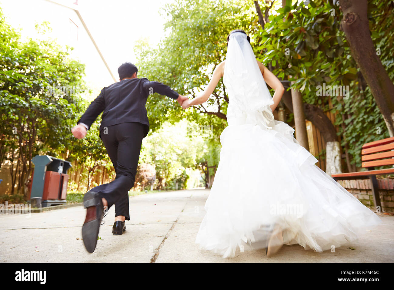 asian wedding couple running on street celebrating marriage. Stock Photo
