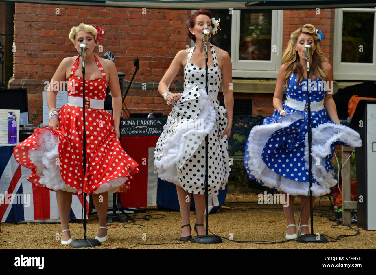 Three women in polkadot dresses, singing 1940s songs Stock Photo