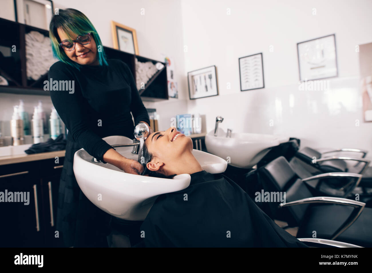 Female hairdresser rinsing hair of a customer . hairdresser washing hair to the customer before doing hairstyle Stock Photo