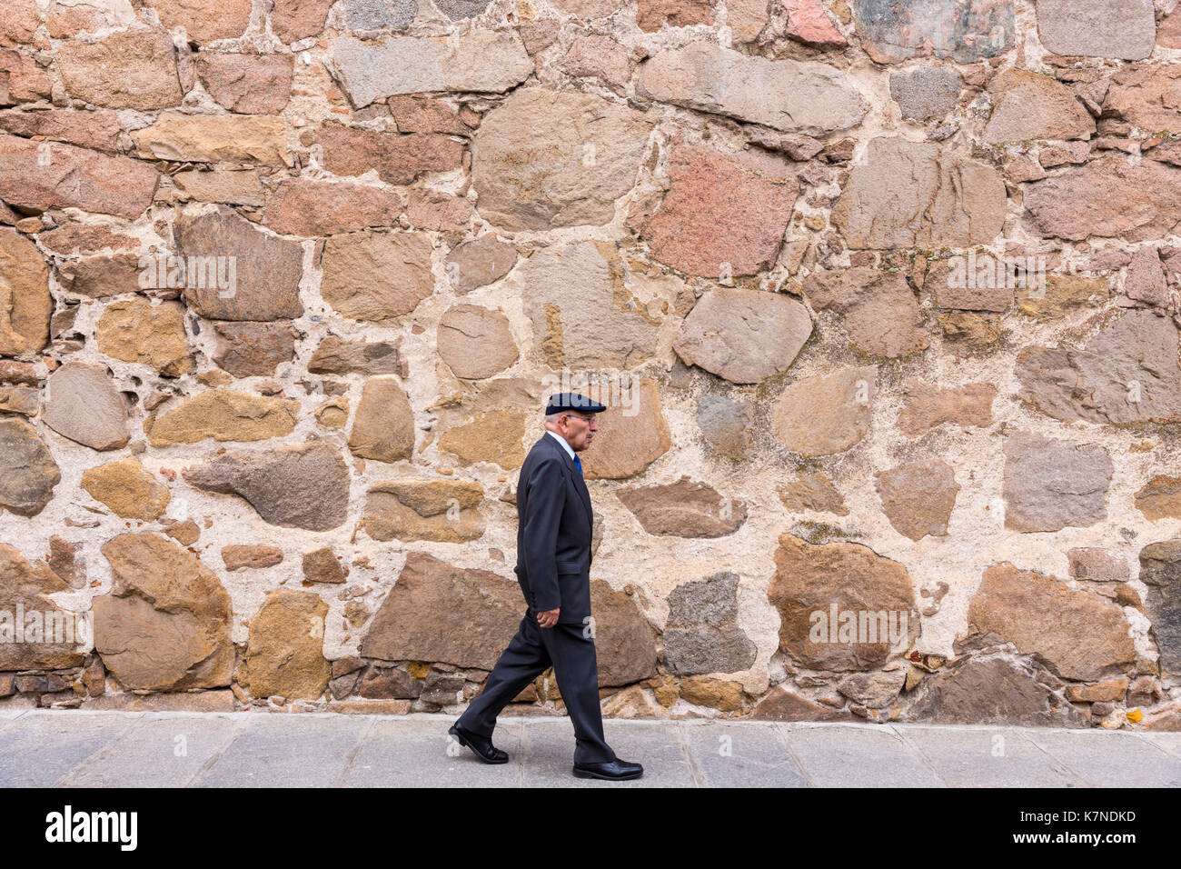 Local people strolling by ancient medieval stone wall of Palacio D'Avila in old town of Avila, Spain Stock Photo
