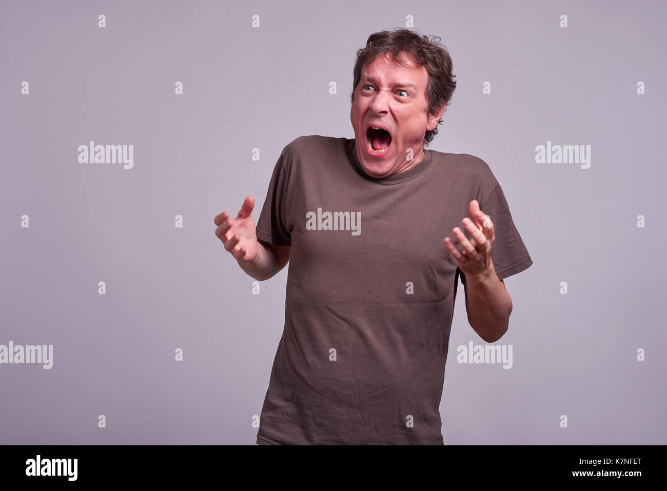 A middle aged man standing and screaming Stock Photo