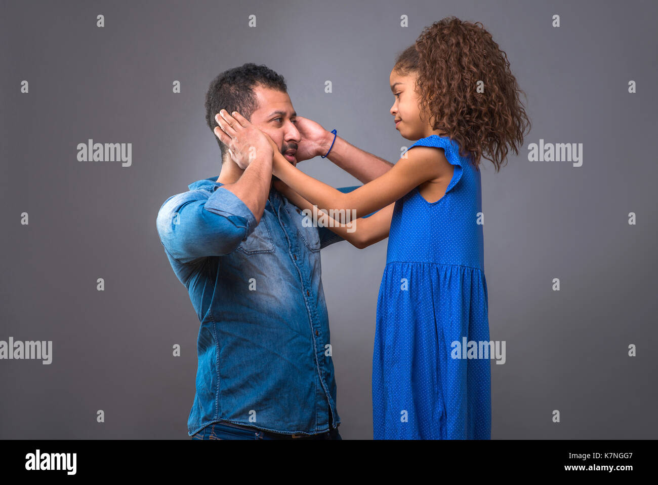 A young black man and his teenage daughter covering his ears with their hands Stock Photo