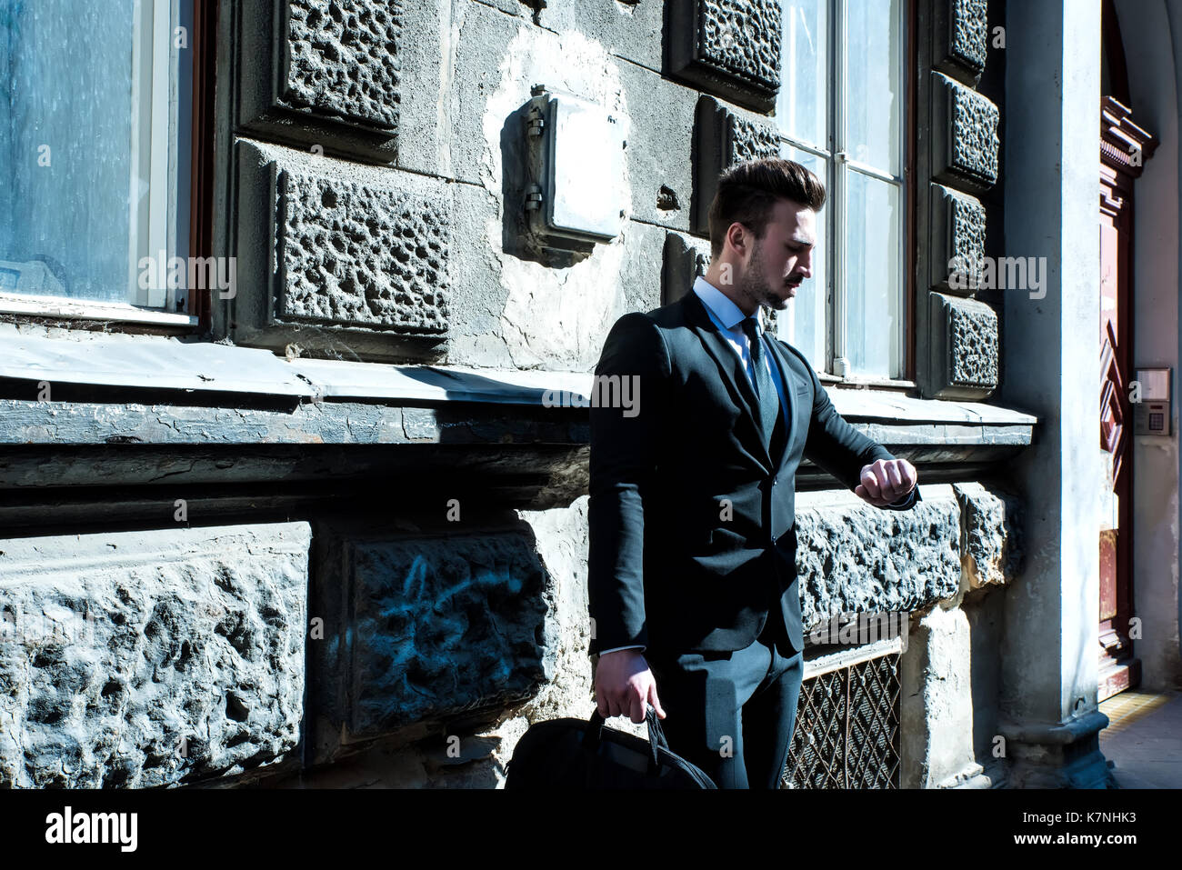 Young businessman waiting outside on the street checking the time on ...
