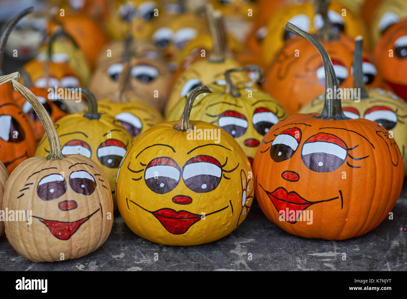 Smiling pumpkins Pumpkins with painted eyes lips nose and eyebrows many multicolor pumpkins many multi-shaped pumpkins many colorful pumpkins Stock Photo