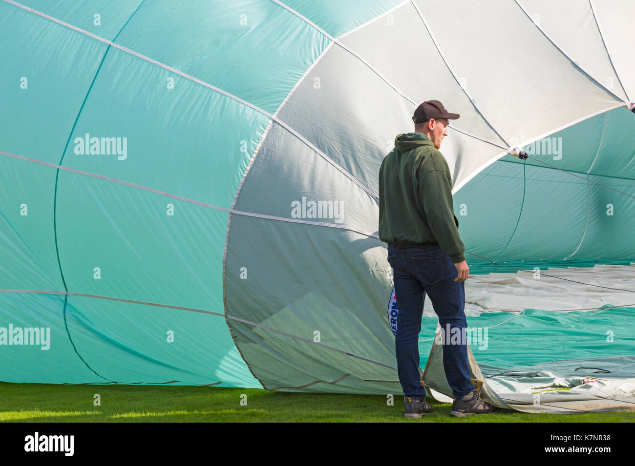 Man standing by turquoise hot air balloon on ground being inflated at Sky Safari hot air balloons festival at Longleat, Wiltshire UK in September Stock Photo