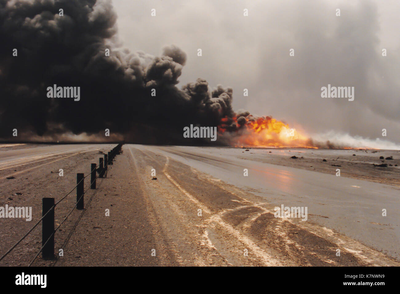 Burning oil well in field coated in spilled oil in aftermath of Operation Desert Storm, Persian Gulf War following the Iraq invasion of Kuwait. Stock Photo