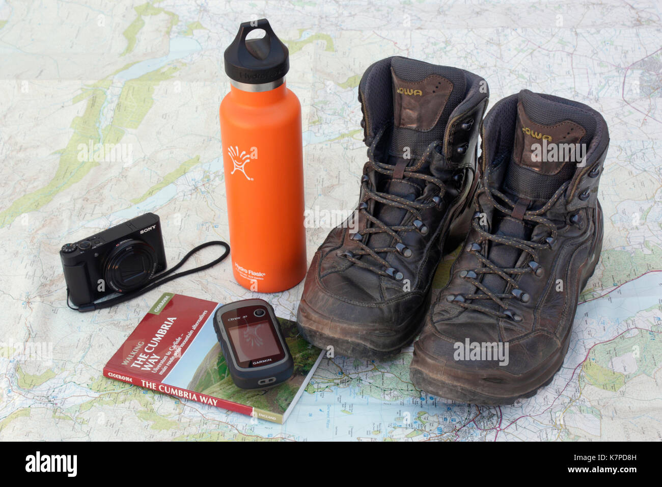 Preparing to walk the Cumbria Way. Hiking boots, water bottle, camera, handheld GPS unit and guidebook on an Ordnance Survey map of the Lake District Stock Photo