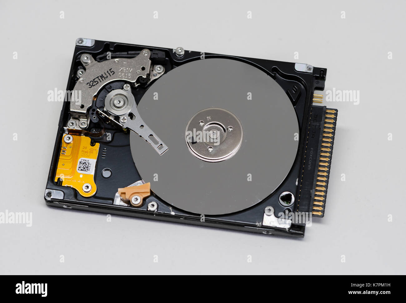 Close-up of an opened computer hard drive disk on clean white background. Read-write head retracted. Stock Photo