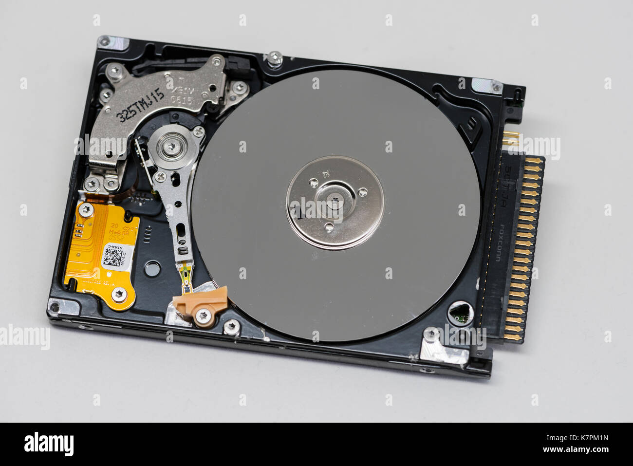 Close-up of an opened computer hard drive disk on clean white background. Read-write head retracted. Stock Photo