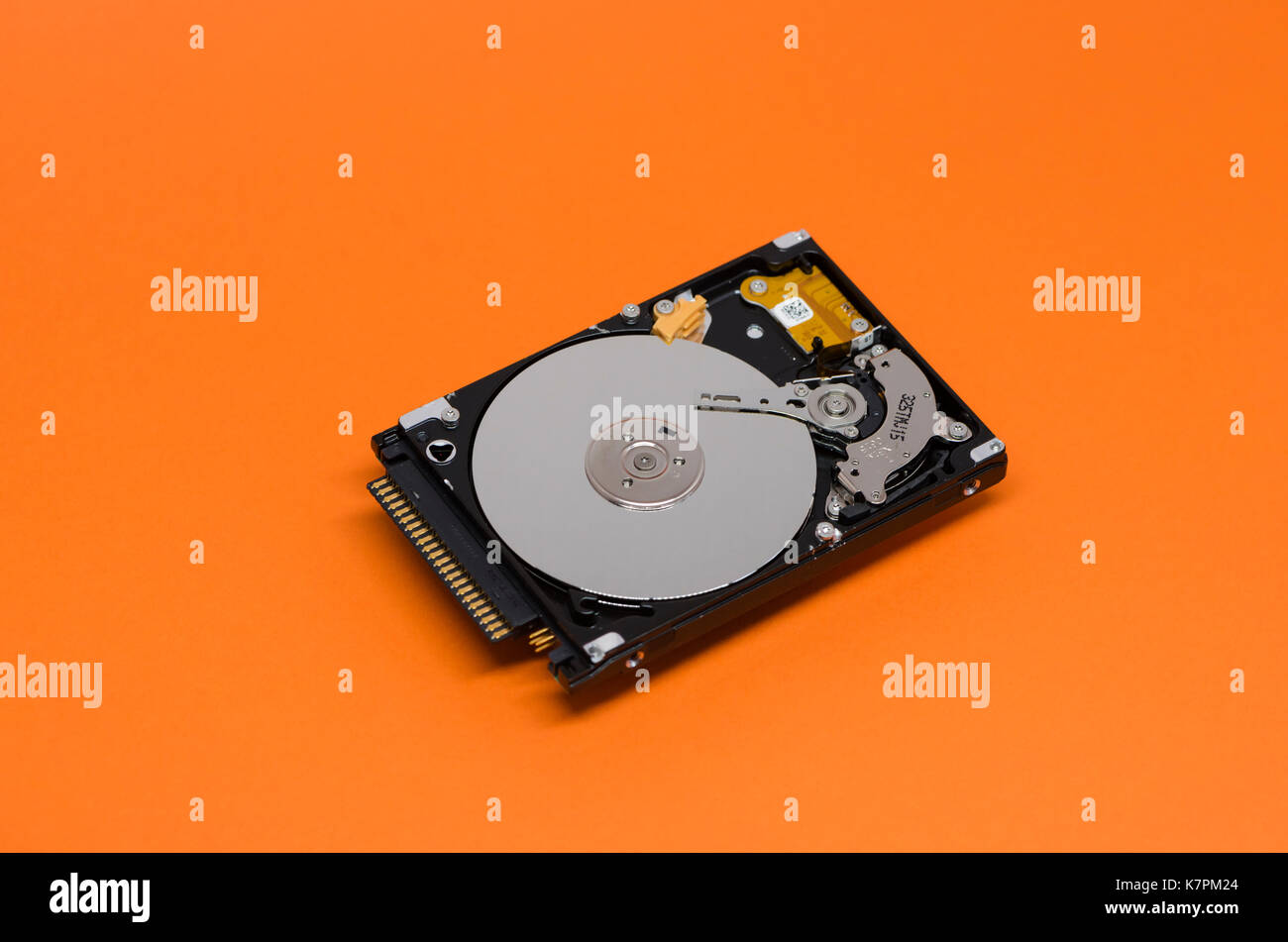 Close-up of an opened computer hard drive disk on orange colored background. Stock Photo
