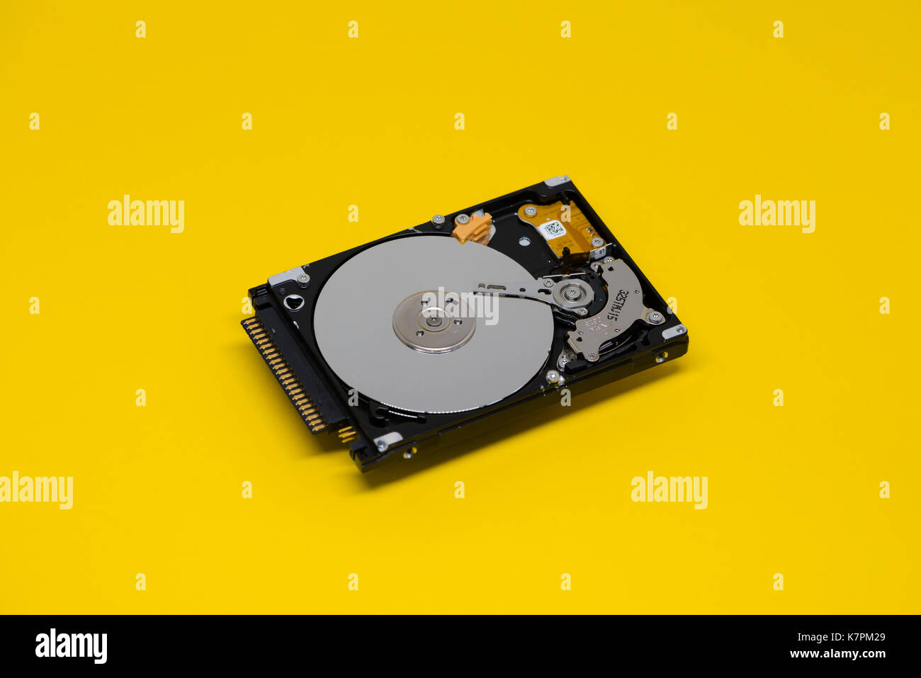 Close-up of an opened computer hard drive disk on yellow colored background. Stock Photo
