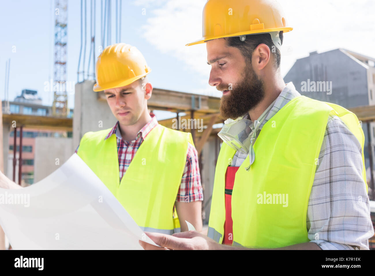 Two young construction workers analyzing together the plan of a  Stock Photo