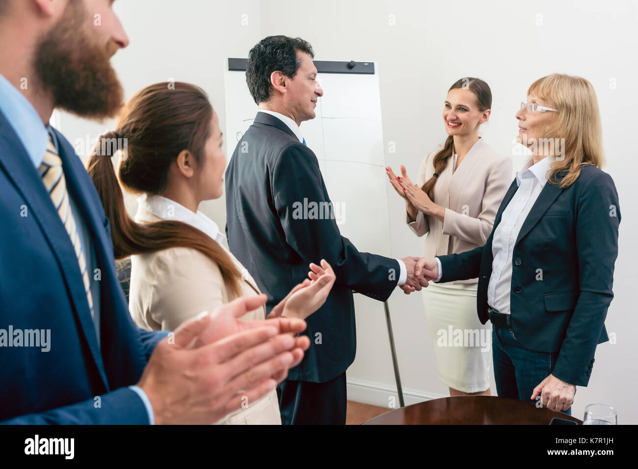 Two middle-aged business associates smiling while shaking hands  Stock Photo