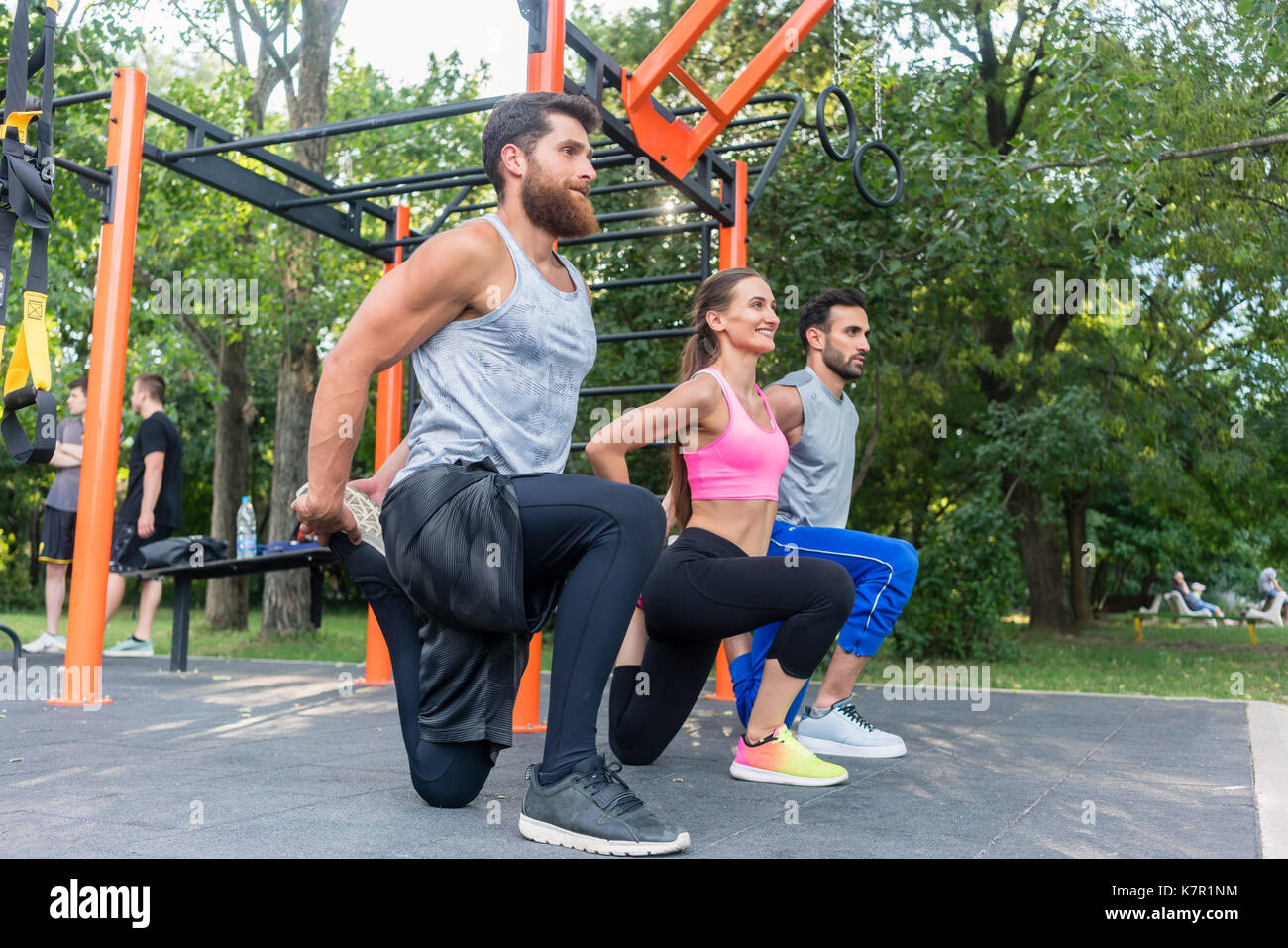 Three determined friends doing stretching exercises for legs as  Stock Photo