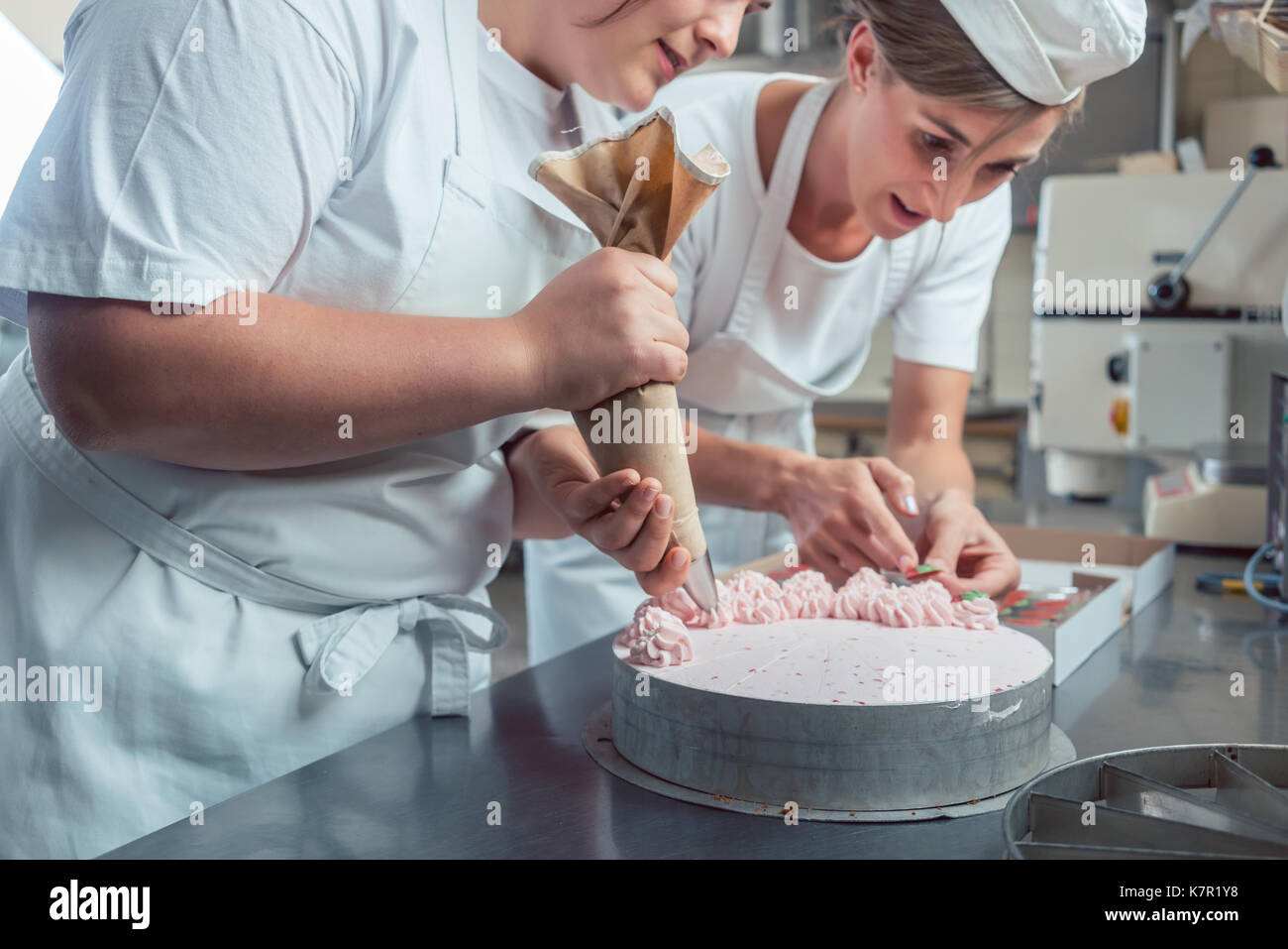 Confectioner women putting cream on cake Stock Photo