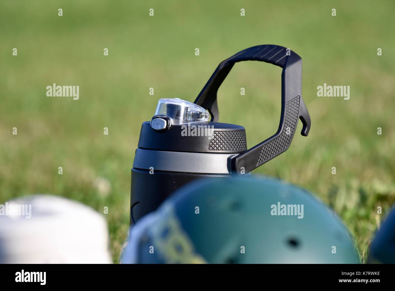 Under Armour water bottle next to football helmet at sports game Stock