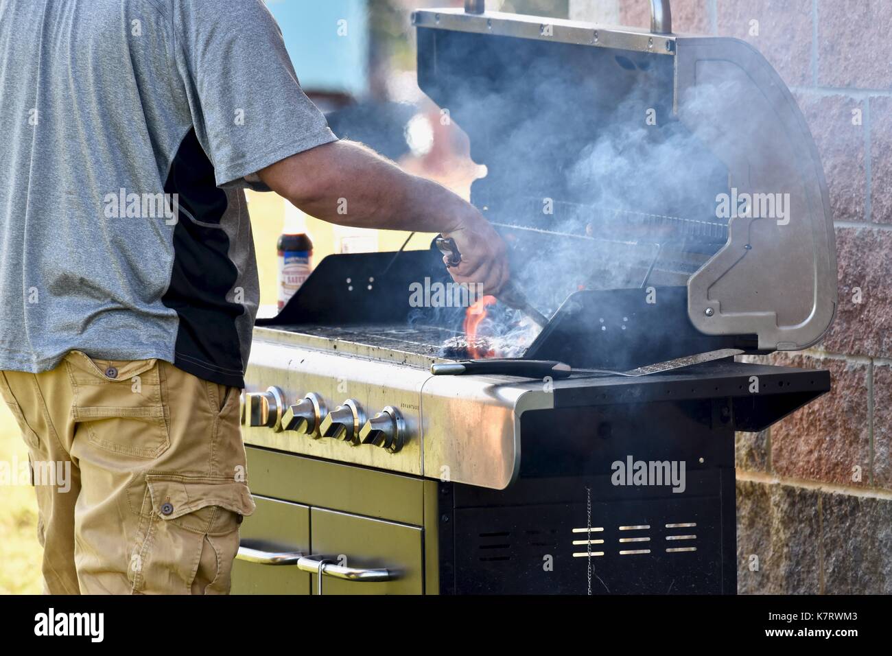 Man using BBQ to grill for barbecue food at concession stands Stock