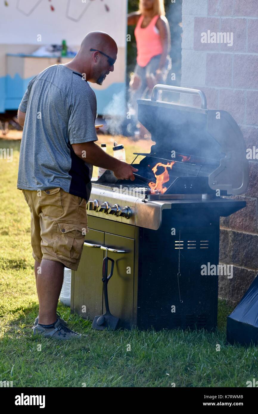 Man using BBQ to grill for barbecue food at concession stands Stock