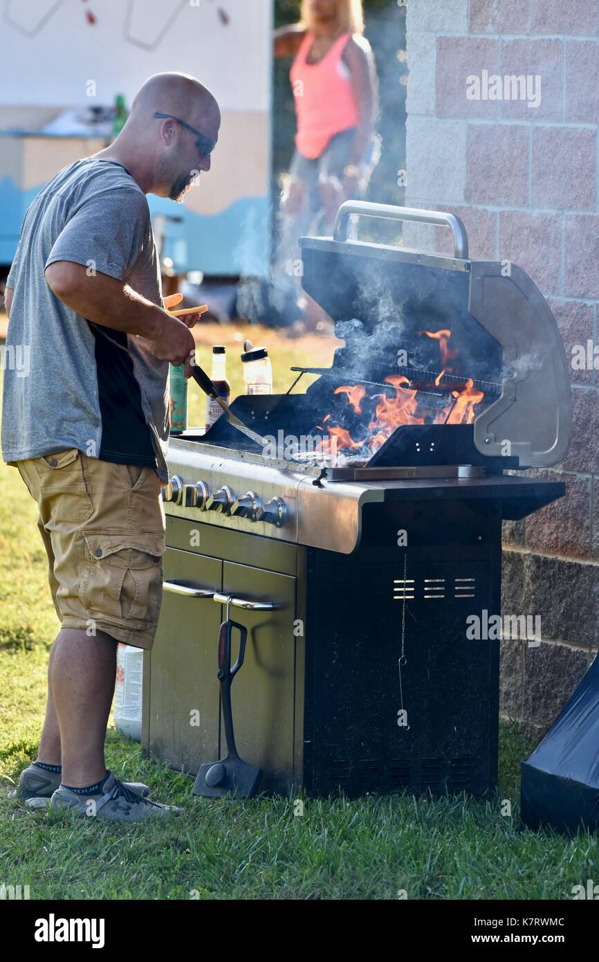 Man using BBQ to grill for barbecue food at concession stands Stock