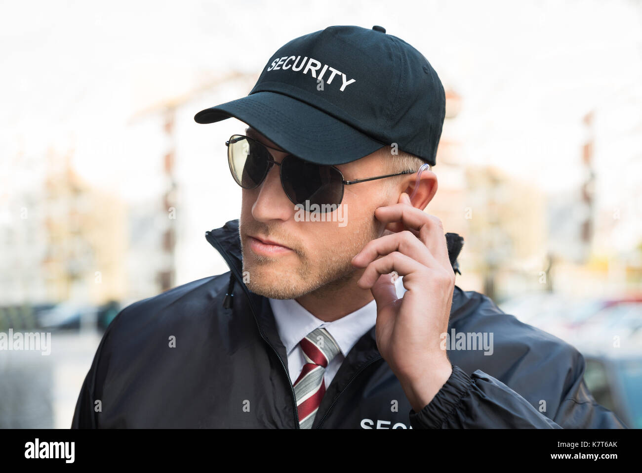 Portrait Of Young Male Security Guard Listening To Earpiece Stock Photo