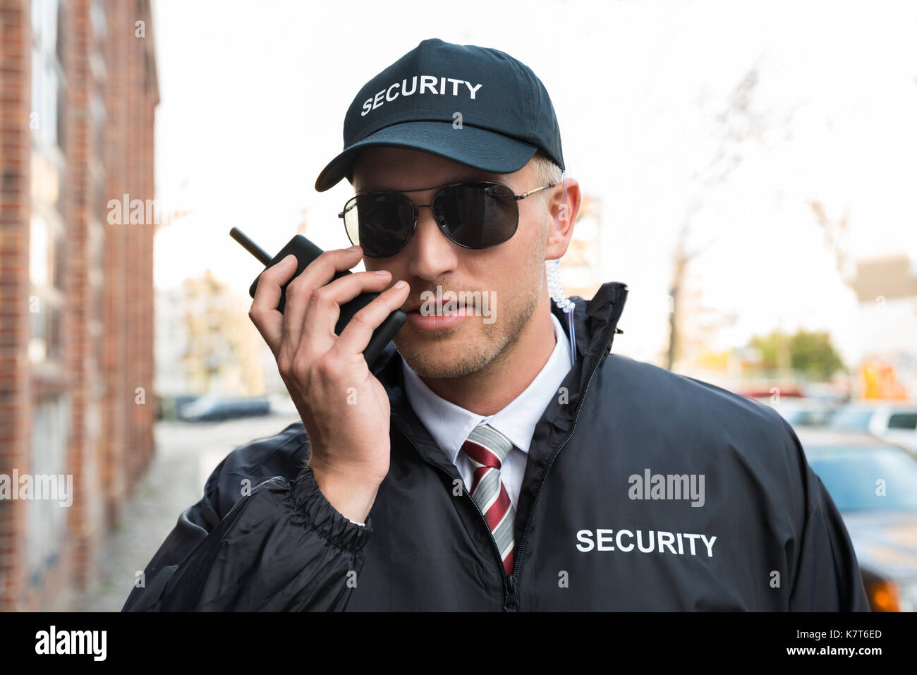 Portrait Of Young Male Security Guard Talking On Walkie-talkie Stock Photo