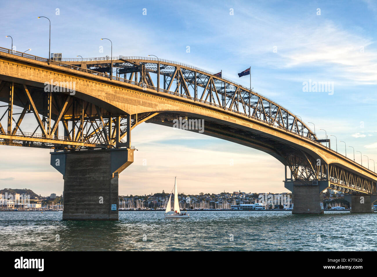 Auckland Harbour Bridge in evening light with yacht passing under. Stock Photo