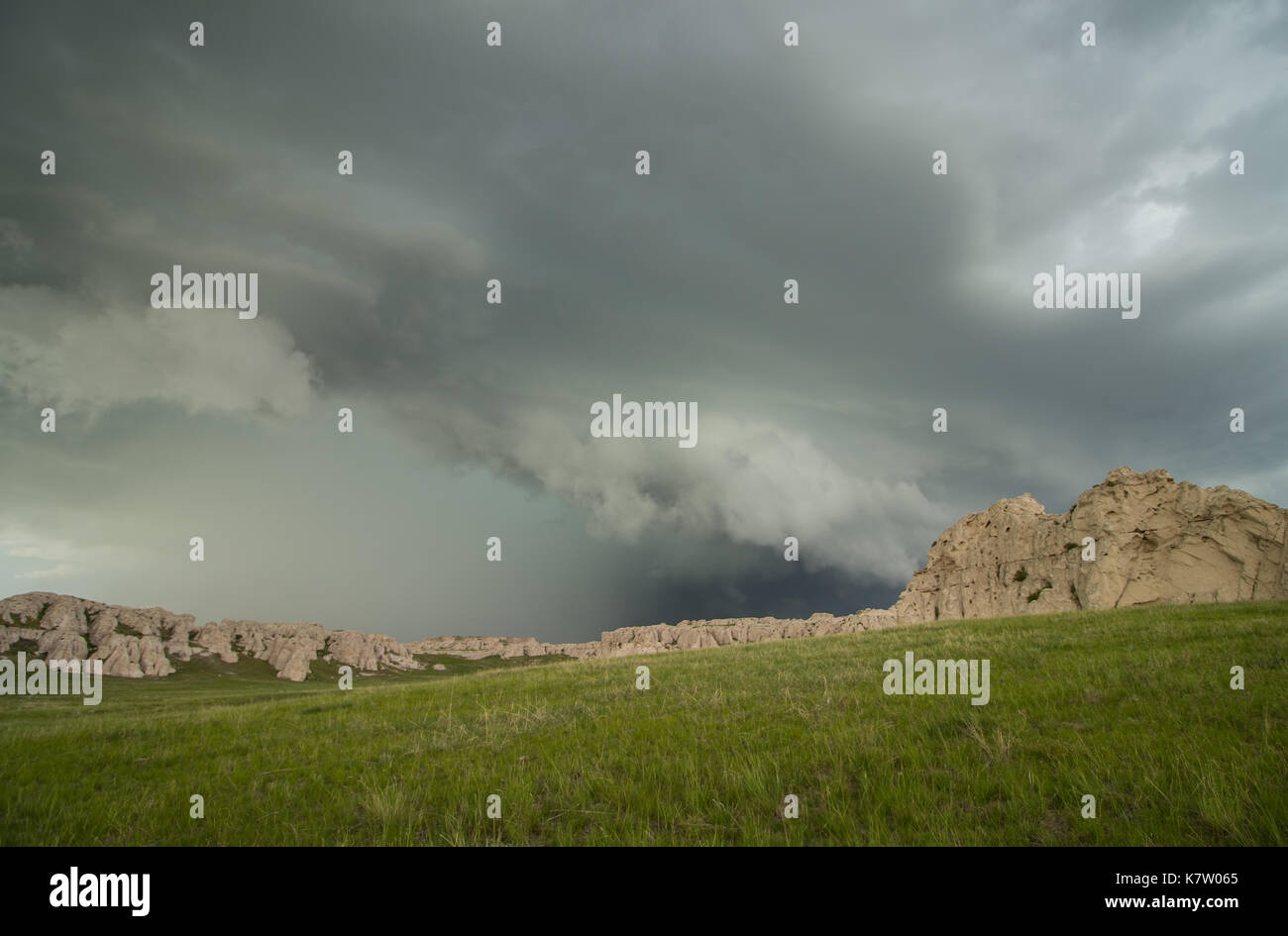 A low and ominous shelf cloud approaches rocky bluffs on a hillside in Nebraska. Stock Photo