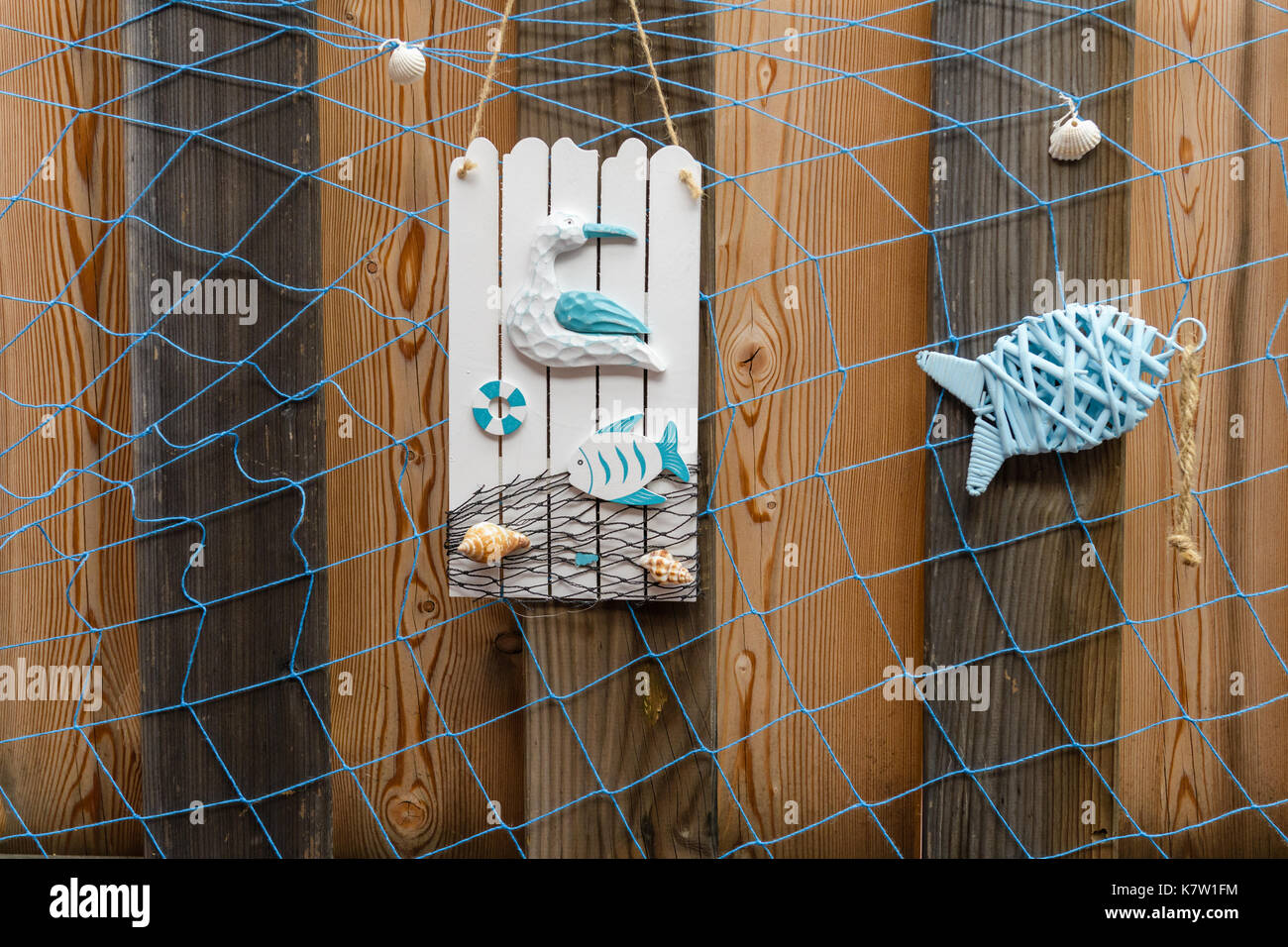Summer beach style decoration with shells, seagull and fish on weathered  wooden background with blue net Stock Photo - Alamy