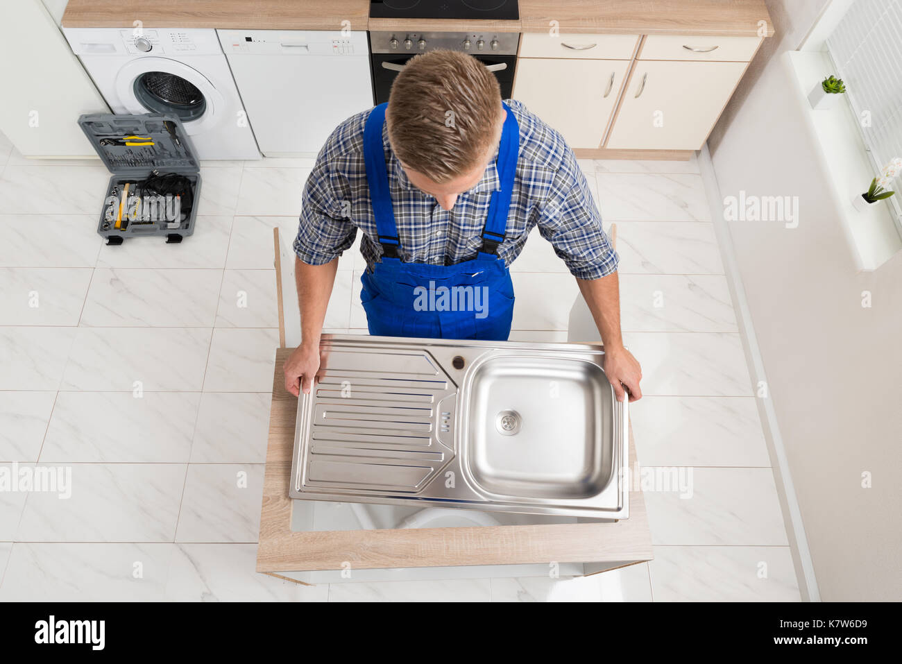 High Angle View Of Male Plumber Fixing Stainless Steel Sink Stock Photo