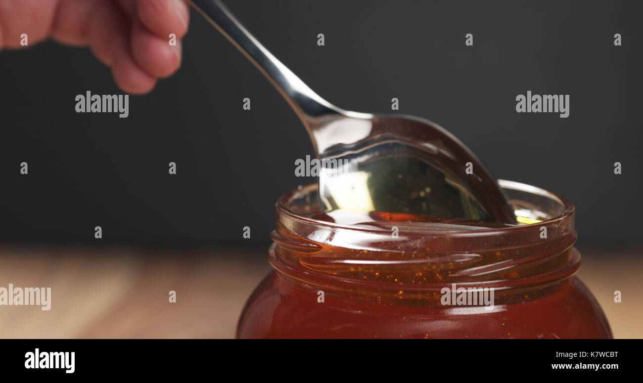 honey pour with spoon in glass jar Stock Photo