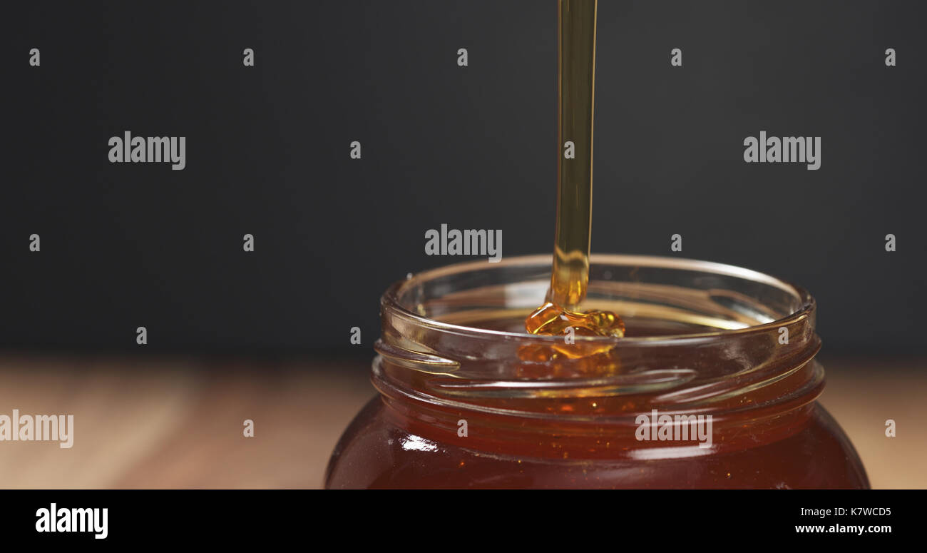 honey pour with spoon in glass jar Stock Photo