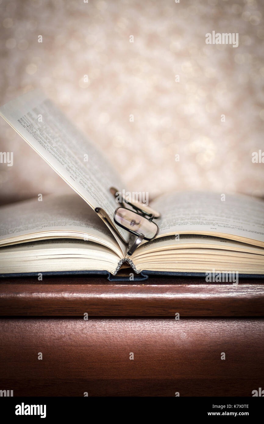 Book and glasses lying on the dresser closeup. Stock Photo