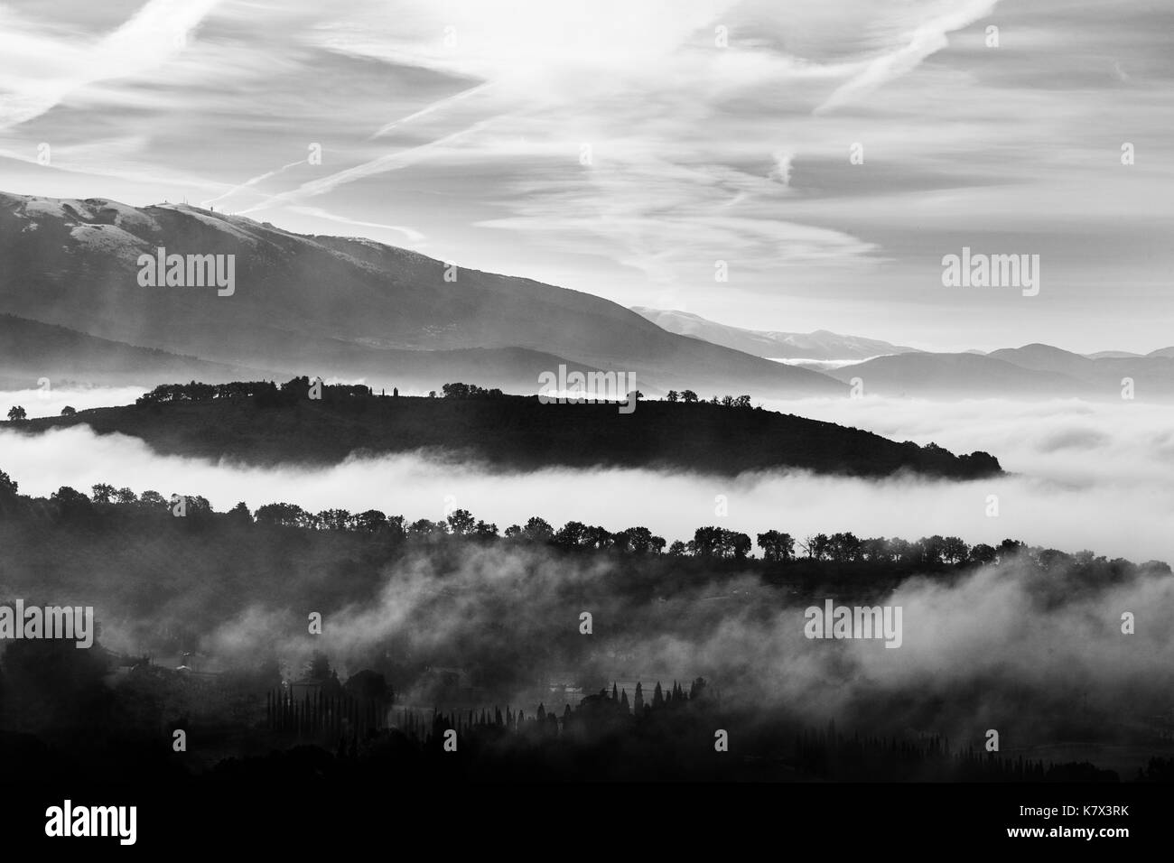 Valley filled by fog with hills and tree emerging from the mist Stock Photo