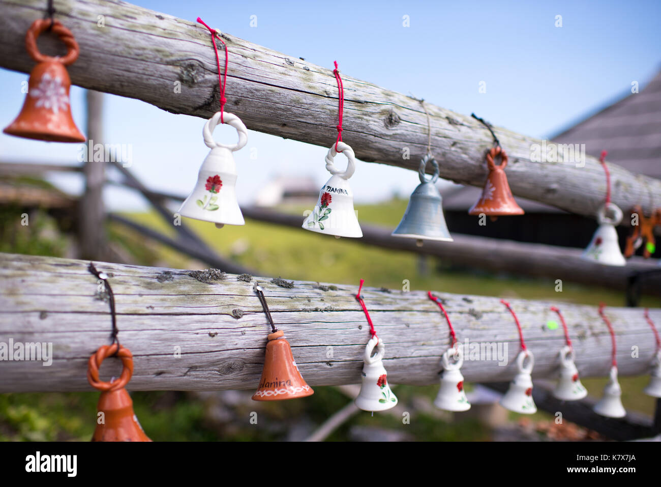 Miniature ceramic cow bells. souvenirs for tourists hanging from wooden fence, typical foe European Alpine Region Stock Photo