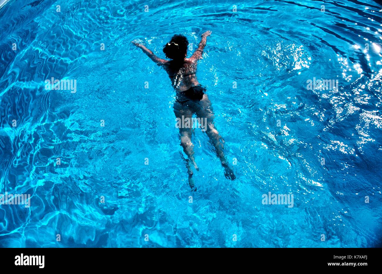 junge Frau in blauem Pool schwimmend,von oben * woman in black bikini swimming in pool Stock Photo