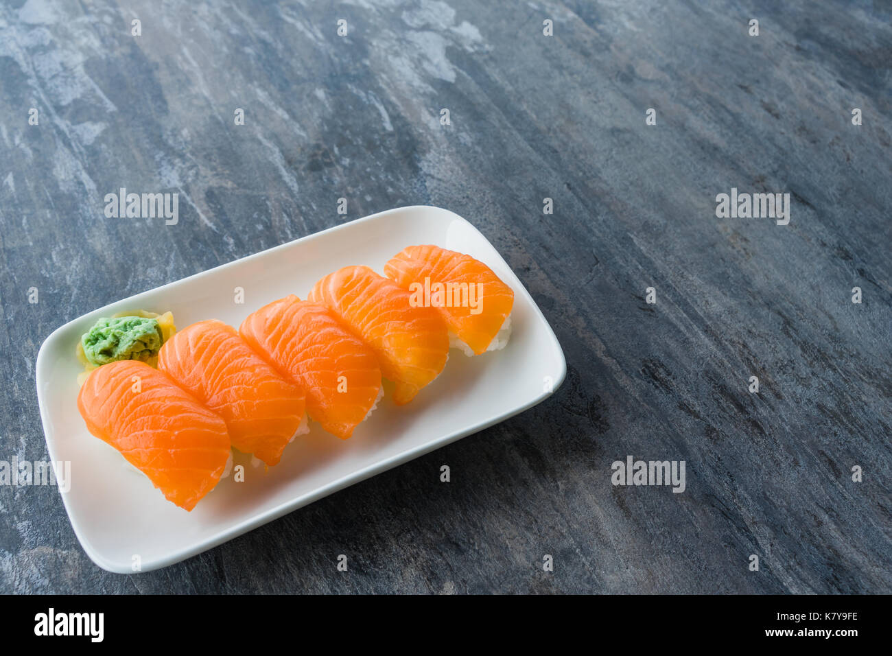 Fresh Japanese Salmon Sushi in white dish with Wasabi and gingers on wood table with copy space Stock Photo