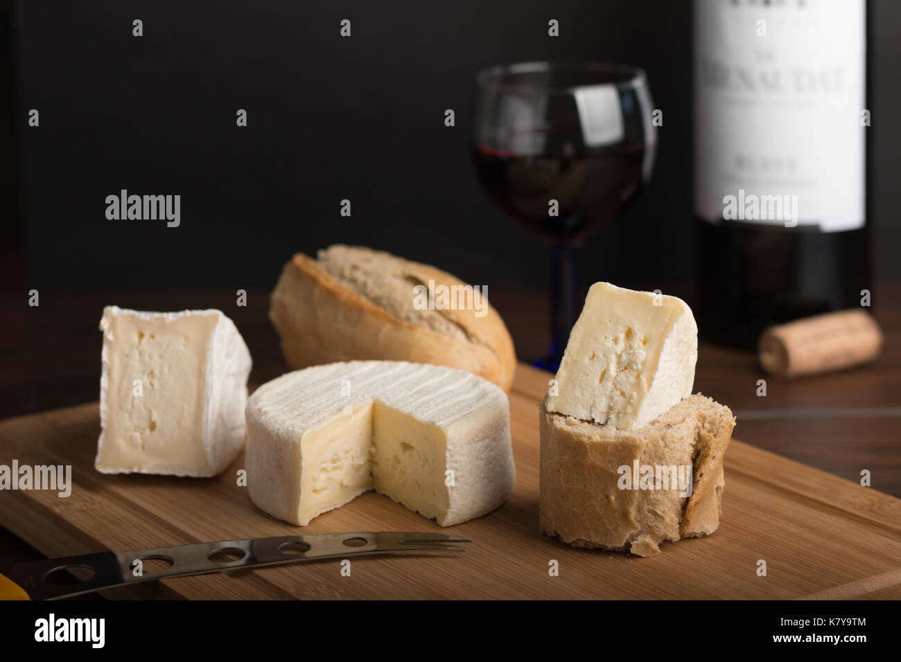 variety of cheese on a wooden plank with wine and bottle Stock Photo