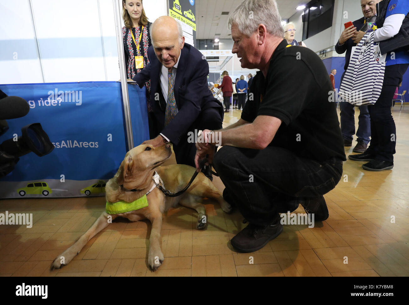 Liberal Democrat leader Sir Vince Cable (left) meets guide dog Natalie on the Guide Dogs stand in the exhibition hall, during the second day of the Liberal Democrats Autumn Conference at the Bournemouth International Centre. Stock Photo