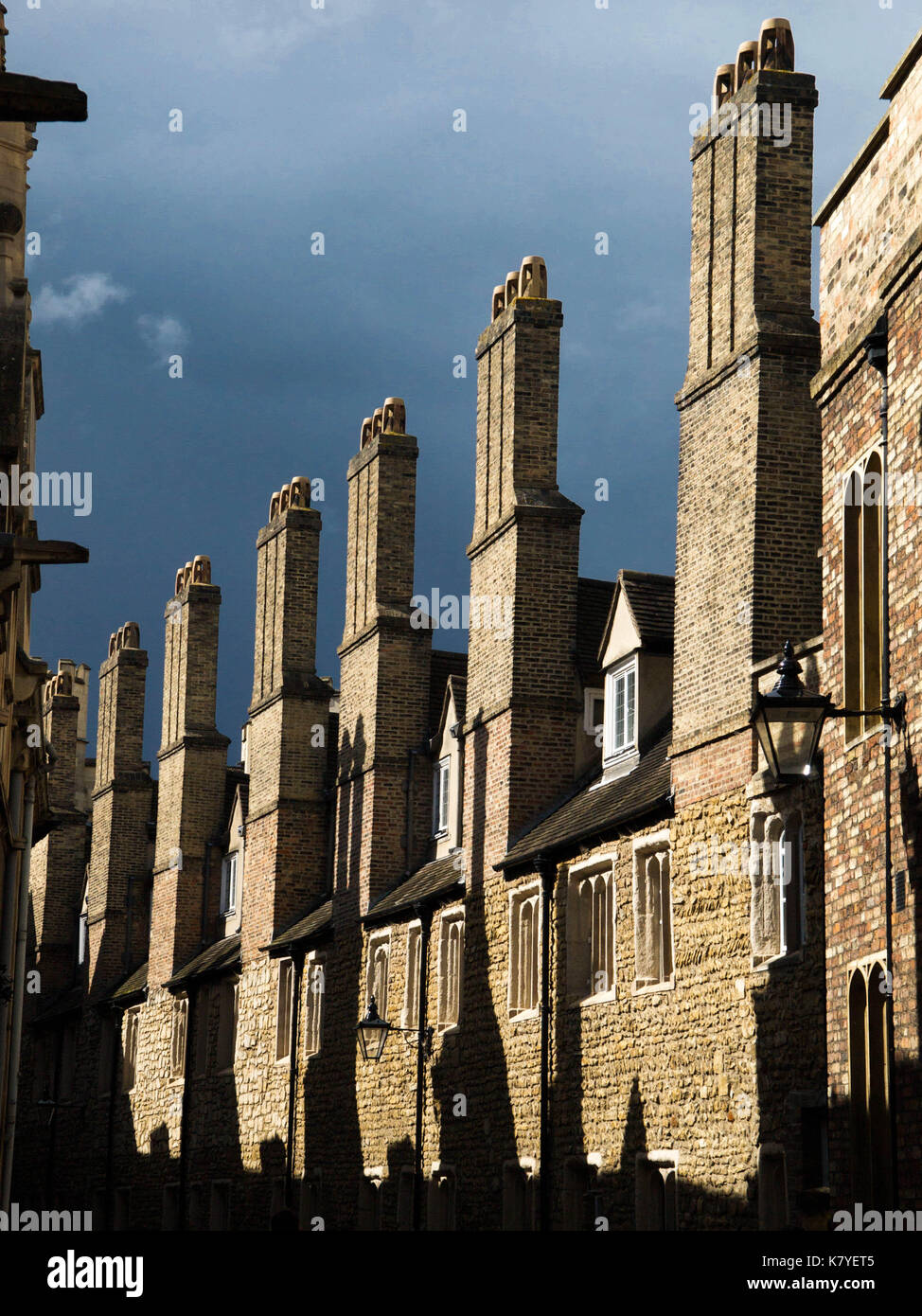Before the Storm: Identical, Old Cambridge Chimneys Stand in Bright Sunshine as Dark Clouds Approach Stock Photo