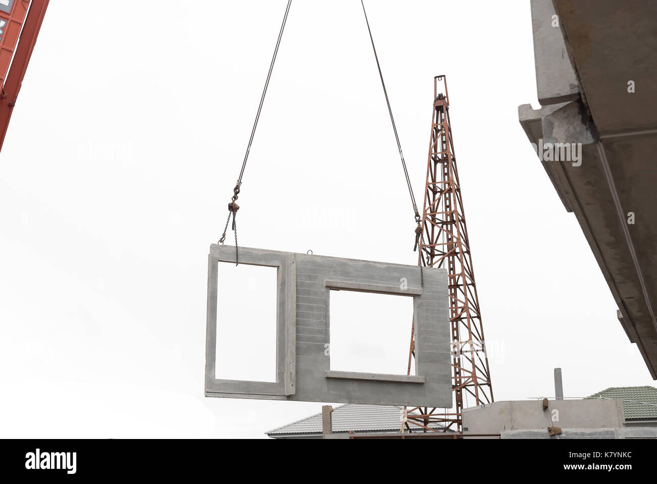 Construction site crane is lifting a precast concrete wall panel to