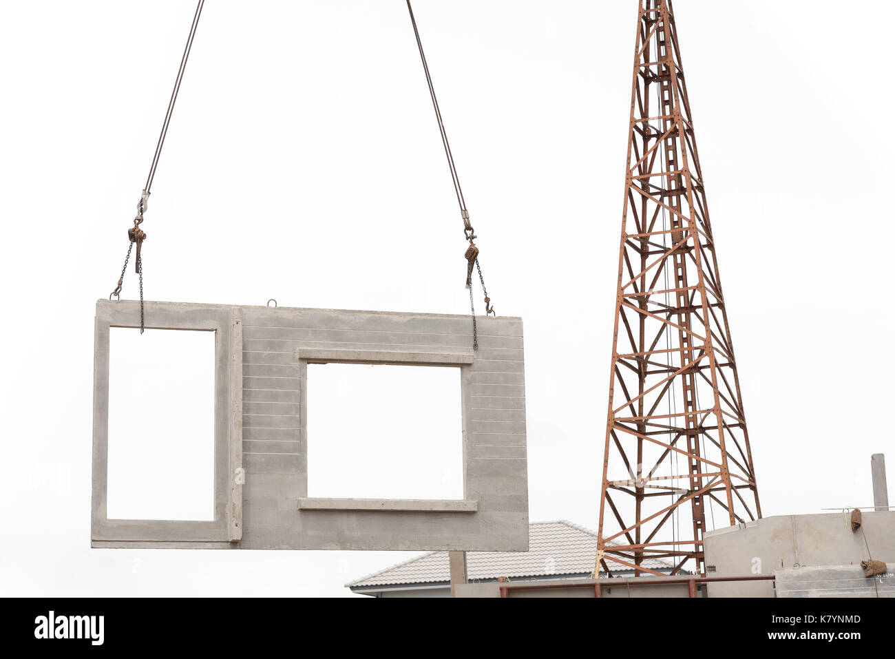 Construction site crane is lifting a precast concrete wall panel to